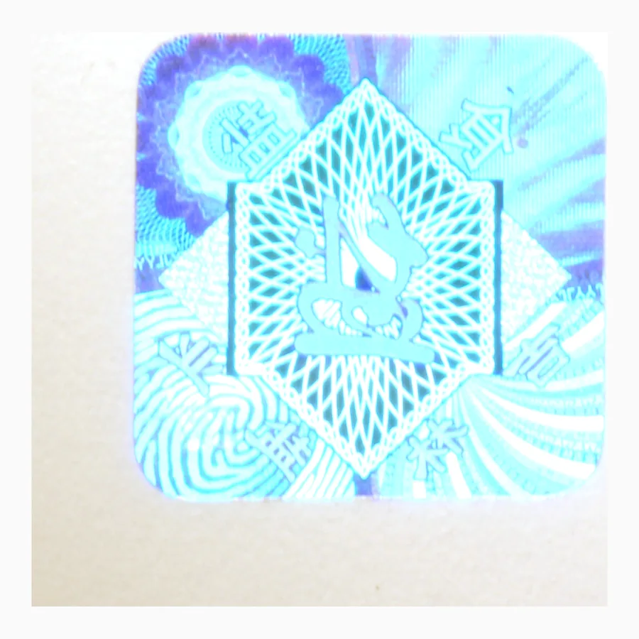 Circular holographic security label showing a radial diffraction pattern shifting through green and gold
